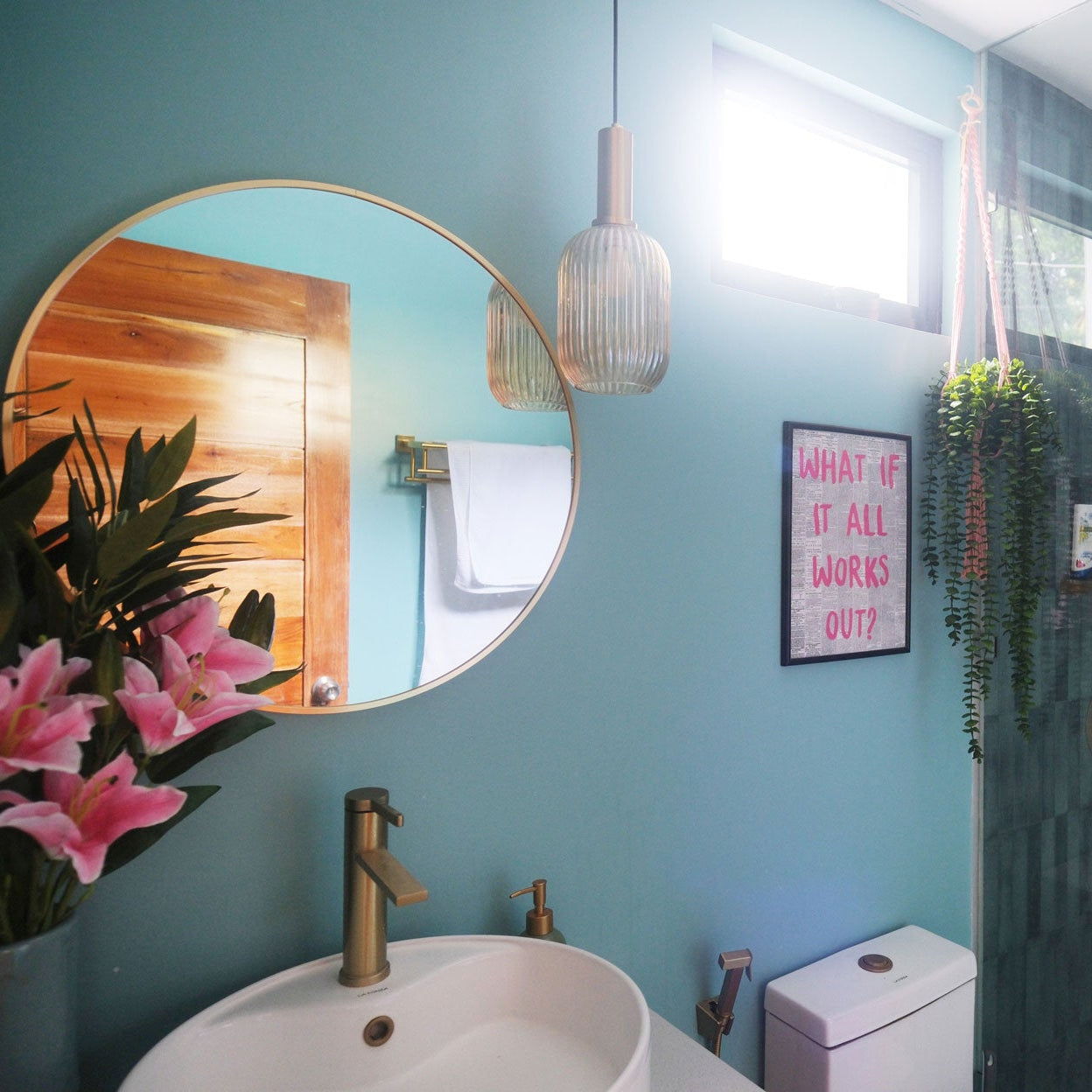 Bathroom interior with teal walls, round mirror, sink, and shower area.