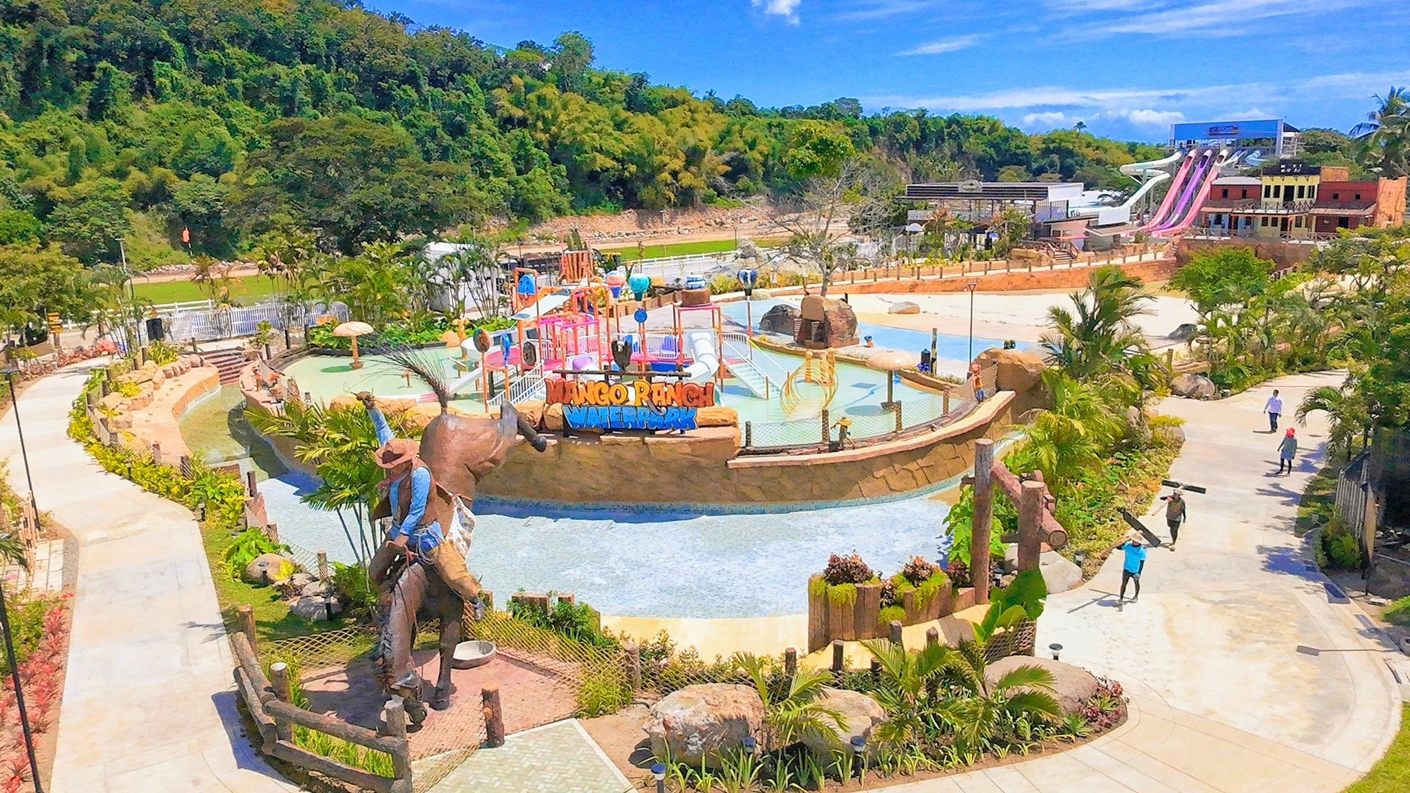 Outdoor water park with slides and pools surrounded by greenery