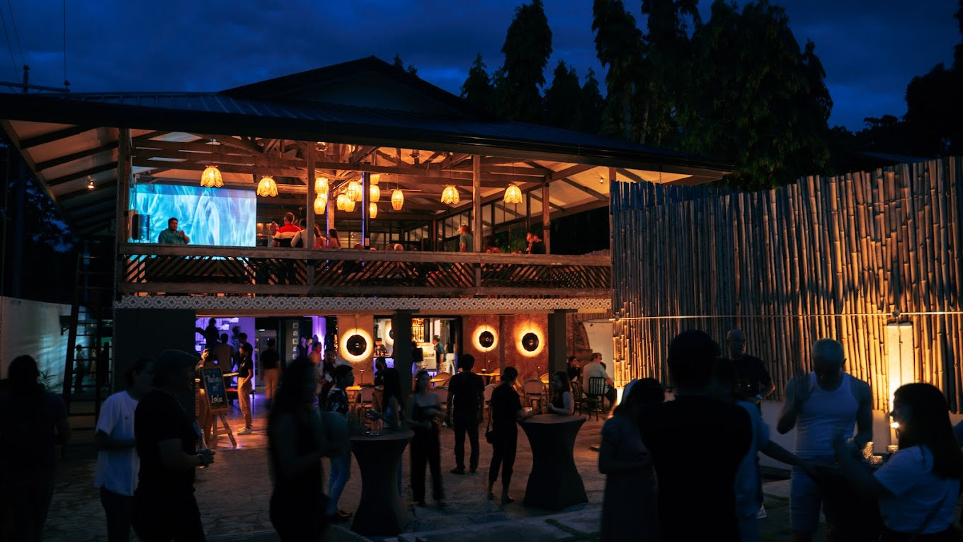 Outdoor evening event with people gathered around a stage and decorations.