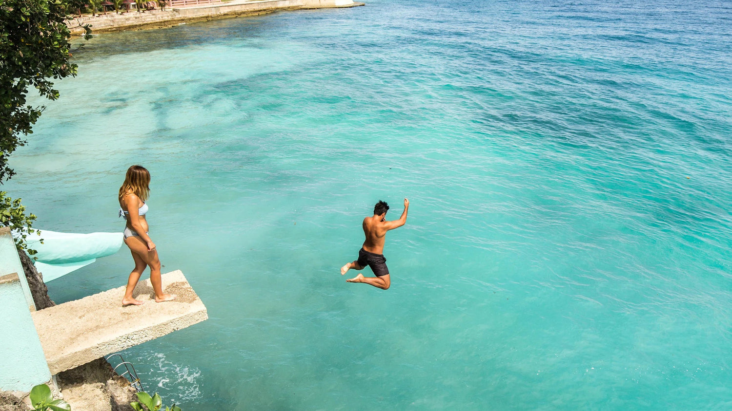 Traveler cliff jumping into turquoise waters at Salagdoong Beach in Siquijor, Philippines.