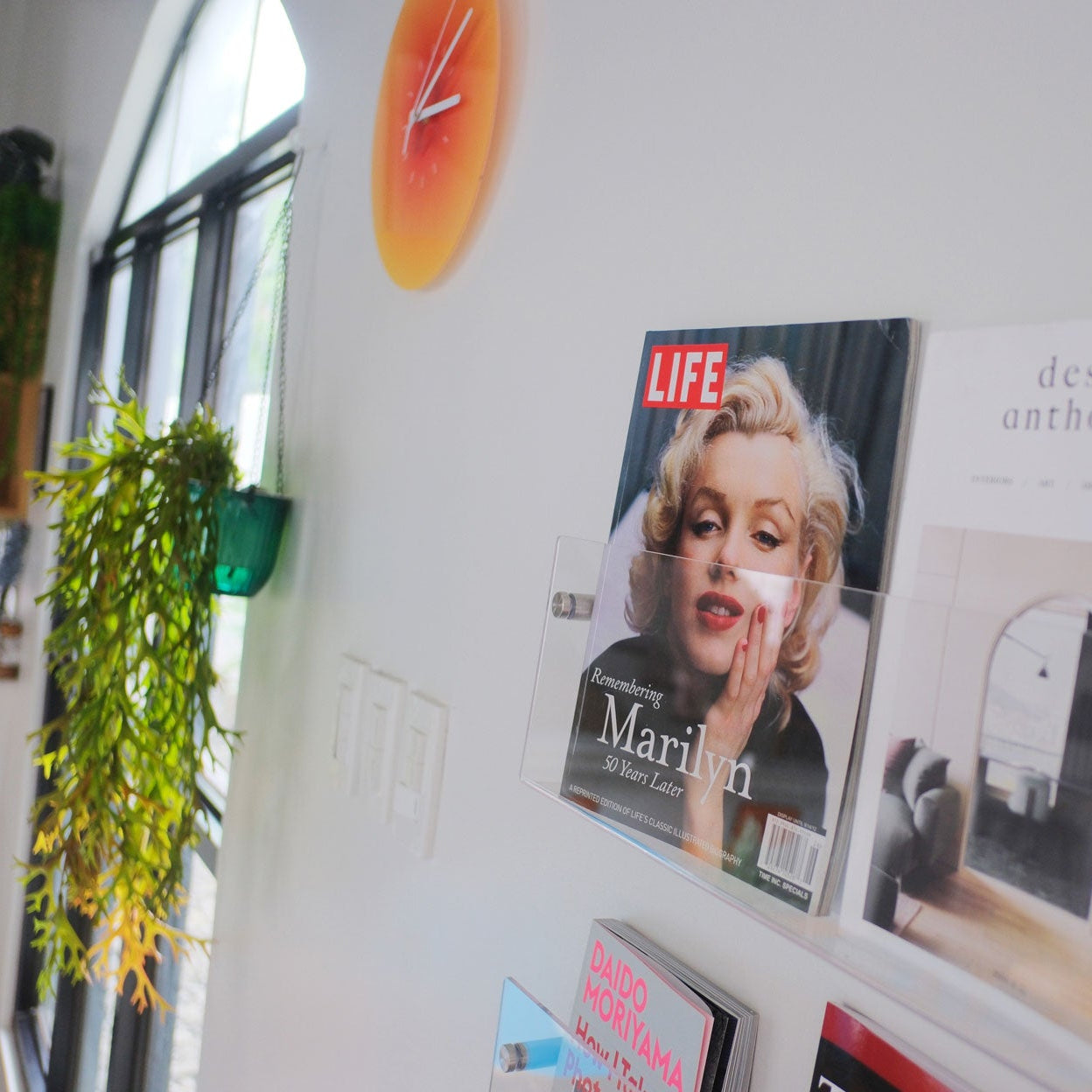 Magazine with a cover featuring a famous actress on a wall next to a clock.