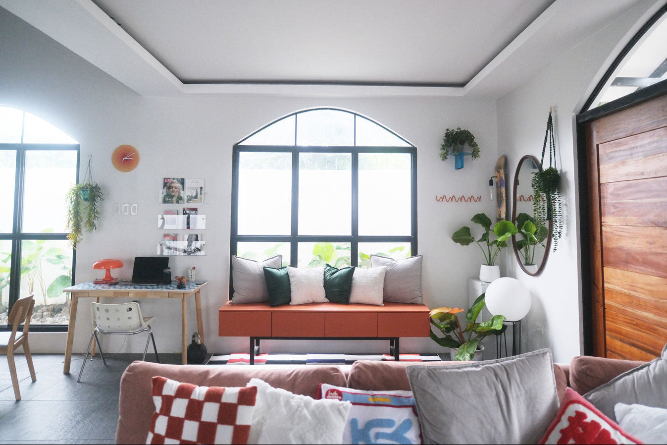 Modern living room with a pink sofa, gray cushions, and a large window.