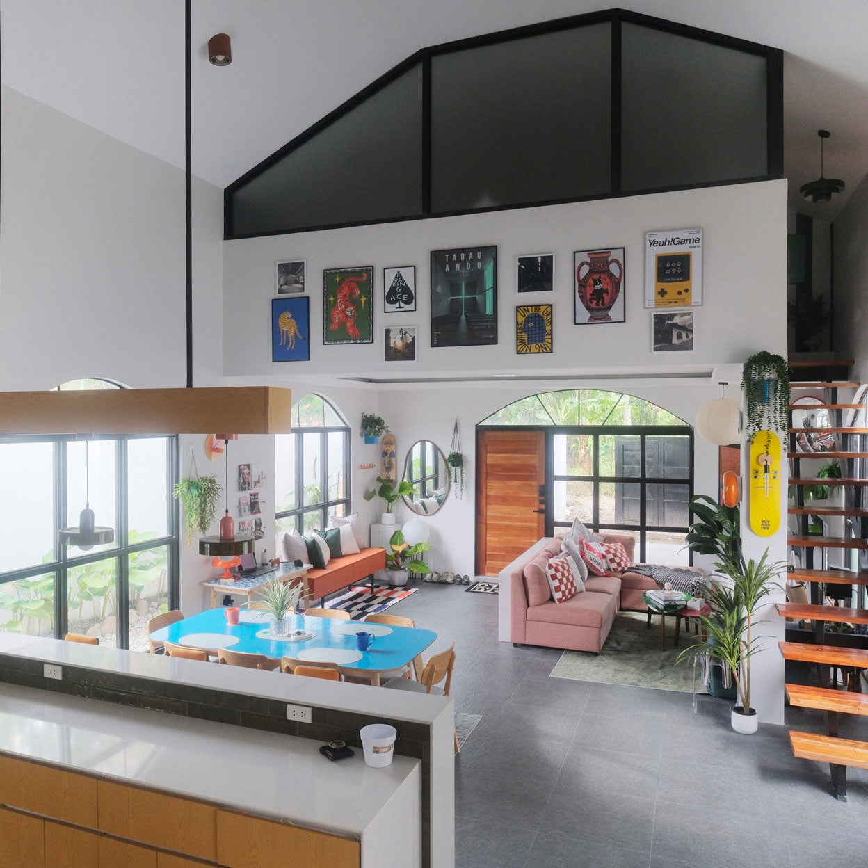 Modern airbnb living room with a large TV, high ceiling. mounted on the wall, bookshelf, and decorative items. Converted chapel airbnb